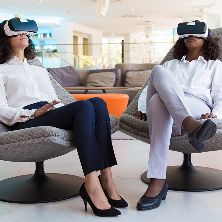 two women sitting in chairs with virtual reality goggles -3